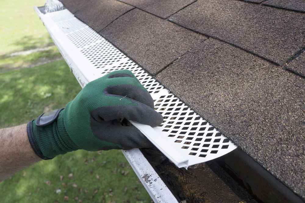 Technician installing gutter guards on a residential roof