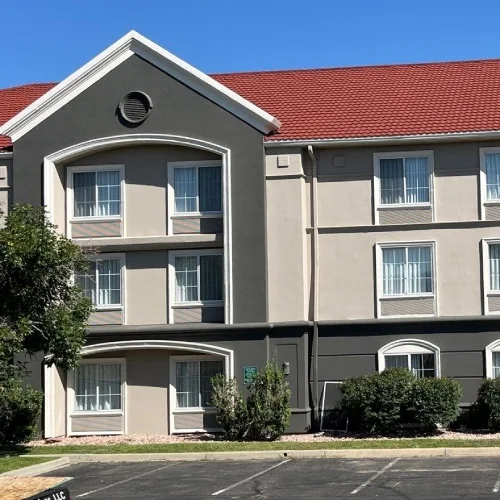 Three‑story hotel with red pitched roof, example for commercial roof replacement guide by Mile High Roofing Services in Westminster, CO