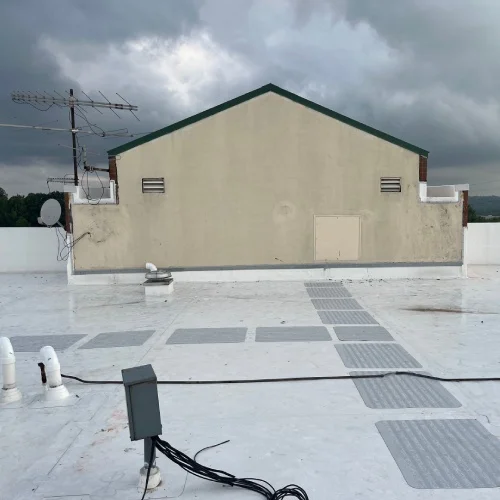 White TPO roof with vents and walkway pads after replacement, commercial roof replacement guide by Mile High Roofing Services in Westminster, CO