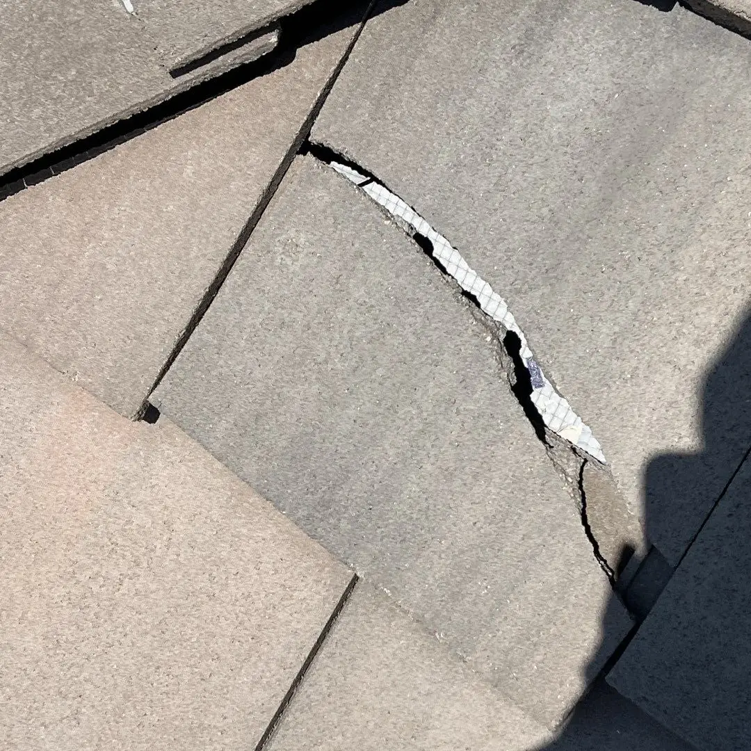 Cracked roof tile damage inspection for roofing referral program by Mile High Roofing Contractor Westminster CO Cracked concrete roof tile exposing underlayment during inspection for roofing referral program by Mile High Roofing Contractor Westminster CO