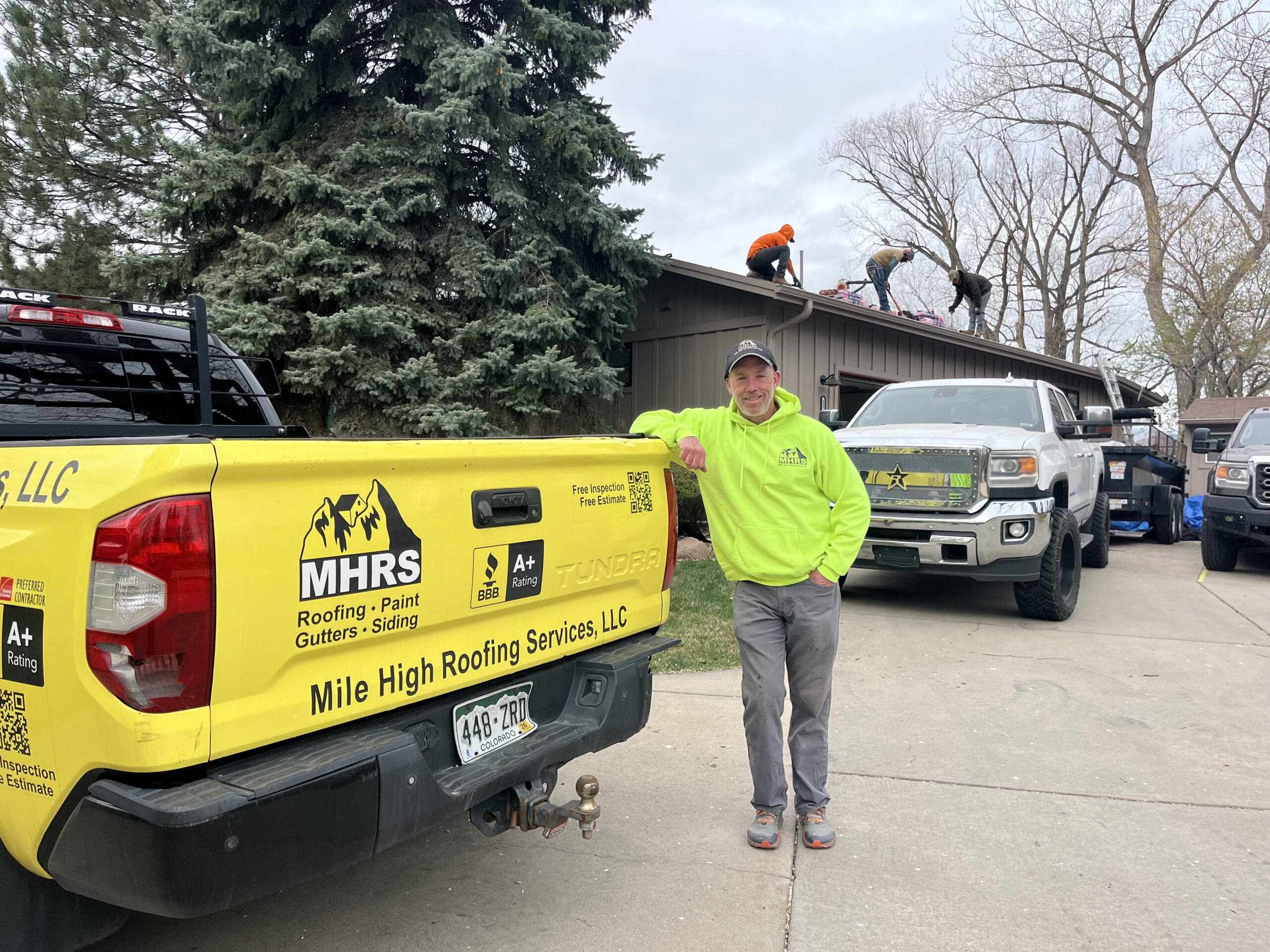 Brian Huelsman Brian Huelsman, Owner, of Mile High Roofing Services standing in front of black and yellow work truck on a jobsite replacing a roof in Westminster, CO